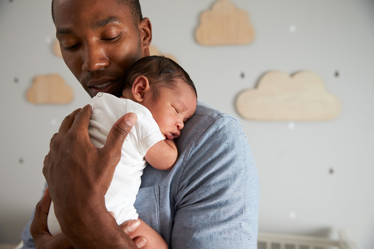 Mit Eltern-Tipps #GemeinsamStärker: Junger Vater mit Baby auf dem Arm.