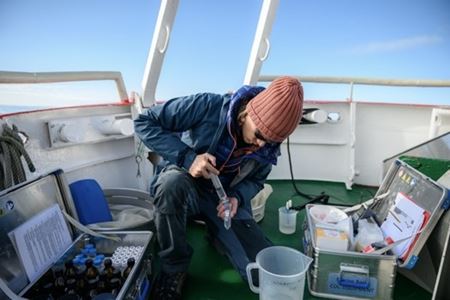 Martin Nielsen verplaatst monsters gevuld met fytoplankton en zoöplankton die hij heeft verzameld op zijn veldlocatie, een sectie van de open oceaan voor de kust van Disko-eiland. Met deze monsters kunnen onderzoekers na verloop van tijd populatieschommelingen en mogelijke verbanden met het veranderende klimaat registreren.