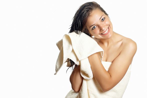 Une fille souriante sortant de la douche se sèche les cheveux