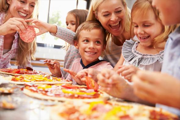Deux mères et 4 enfants composent des pizzas.
