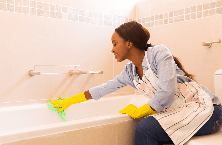 Was hilft gegen Kalk? Junge Frau reinigt ihr Bad von Kalkablagerungen