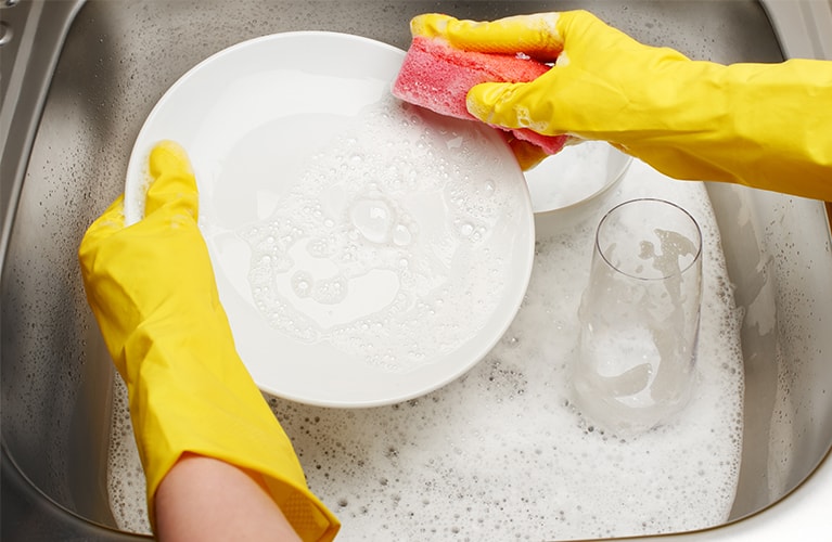 Geschirrspülmittel: junges Paar beim Abwasch  Geschirrspülmittel: Hände spülen einen Teller mit Spülmittel 