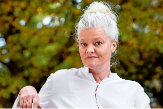 Eine Frau über 50 schaut nach links und lacht. Ihre grauen Haare trägt sie in einem Dutt.