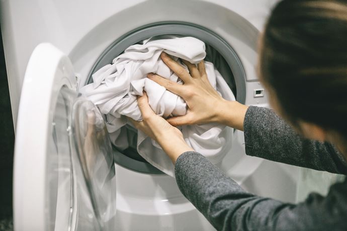 Persona metiendo ropa blanca en una lavadora
