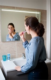 Femme face a un miroir se brosse les dents