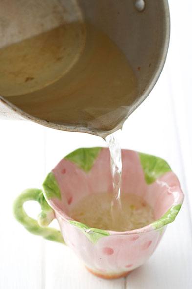 Quelqu'un verse de la cire fondue dans une tasse de thé colorée