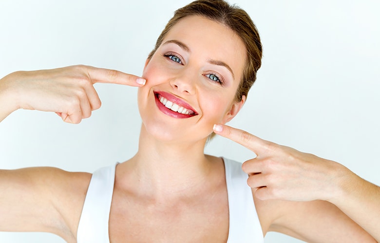 Γυναίκα χαμογελάει και δείχνει τα περιποιημένα δόντια της